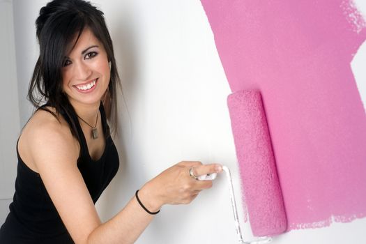 A brunette woman paints the wall of her apartment