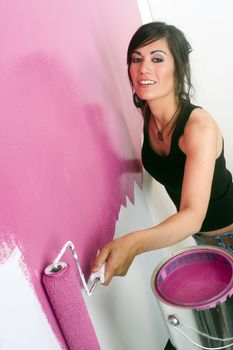 A brunette woman paints the wall of her apartment