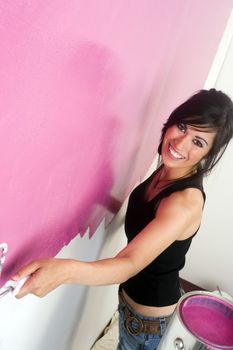 A brunette woman paints the wall of her apartment