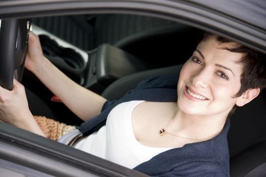A beautiful thirty something woman holds the steering wheel