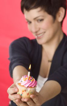 A pretty brunette holds her birthday cupcake