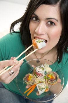 A 29 year old woman takes a bite of a Sushi Roll