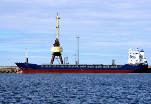 The cargoship and the crane on a background of the  sky