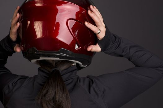 A red full face helmet is put on by a woman rider