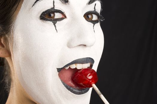 A Mime enjoys a lollipop in an up close portrait.