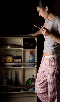 Woman in her pajamas goes into the refrigerator