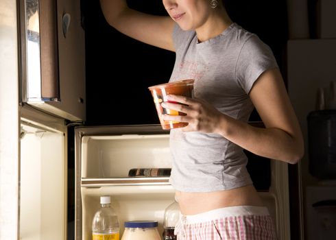 A woman prowls the refrigerator late at night