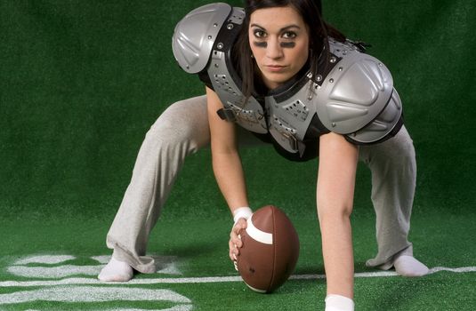 A woman crouches in a football pose as a center