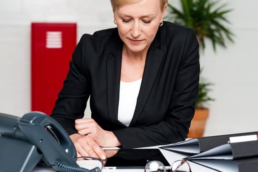 Female executive sitting in office looking down at tablet screen