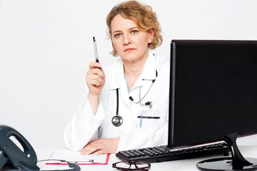 Serious aged doctor posing with pen in hand, showing it to camera