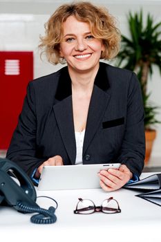 Corporate lady operating wireless tablet device. Indoor office shot