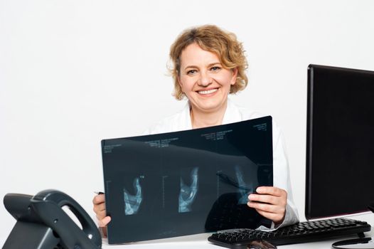 Experienced female surgeon holding patients x-ray report and smiling at camera