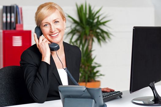Secretary talking on phone with client, looking at you