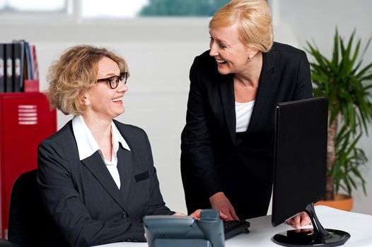 Joyful businesswomen enjoying at work desk during office hours