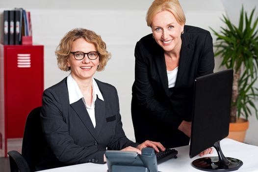 Woman working in office with colleague in front of computer