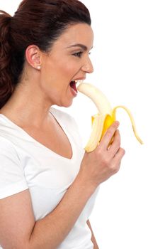 Side view of brunette women eating banana, isolated on white background