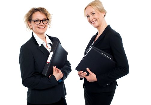 Happy middle aged business females holding files and looking at camera
