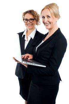 Side view portrait of two corporate women working on laptop isolated against white background