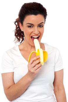 Beautiful young fit girl eating banana isolated on white background