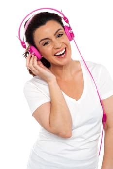 Profile shot of a cheerful young beautiful lady enjoying music on her pink headphones