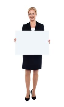 Full length portrait of businesswoman showing blank white billboard. Indoor studio shot