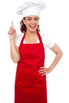 Beautiful smiling female chef indicating upwards isolated on white background