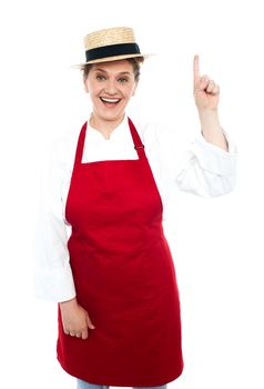 Joyful middle aged cook pointing upwards. Indoor studio shot