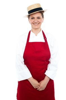 Smiling middle aged female chef wearing hat and dressed in white and red uniform