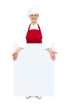 Female cook showing white blank ad board, full length shot