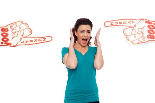 Woman shouting loud, stuck in between two large hurray boo foam hands pointing at her