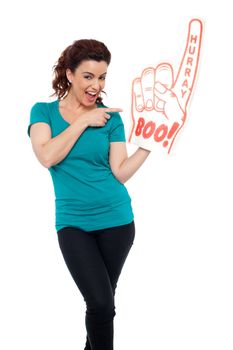 Smiling young woman pointing at large foam hand isolated against white background