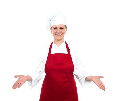 Senior smiling female chef standing with open palms looking at you