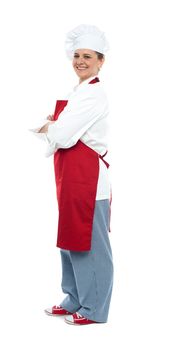 Side view of confident middle aged female chef posing with arms crossed looking at you