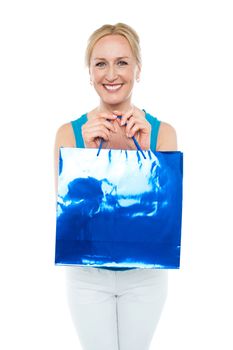 Happy aged woman carrying shopping bag looking at camera