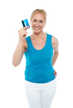 Trendy middle aged woman showing credit card to camera with hand on her waist