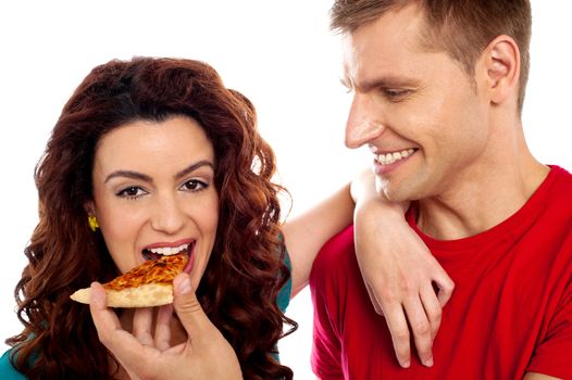 Girl enjoying pizza piece shared by her boyfriend. Great love couple