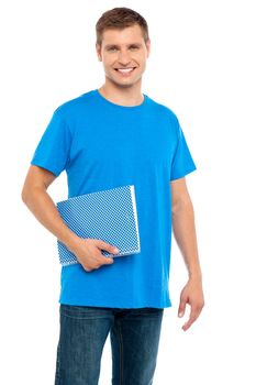 Smiling guy holding spiral notebook isolated over white background