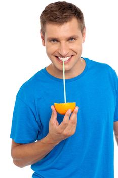 Cool guy sipping juice from half orange, using straw to sip