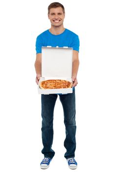 Casual guy showing freshly baked yummy pizza kept in open box. Full length shot