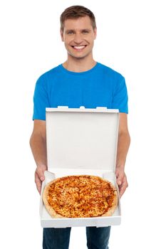 Smiling casual man offering pizza to you and looking at camera