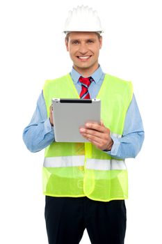 Happy male construction engineer with safety hat holding a wireless device