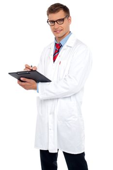 Handsome doctor writing prescription looking at you