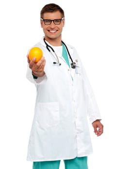 Happy young doctor offering you orange isolated over white