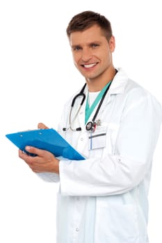 Smiling young doctor writing on clipboard isolated against white background