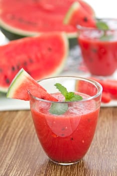 Fresh Watermelon smoothie with mint on top by some fresh pices of watermelon