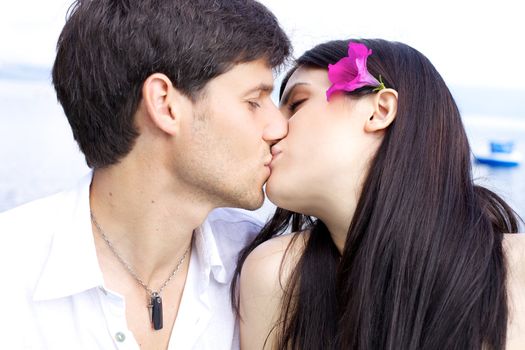 Beautiful woman kissing her boyfriend with flower in her hair