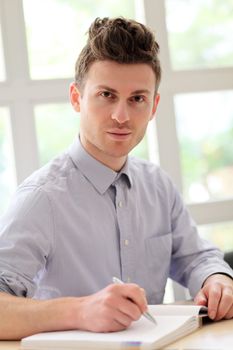 Young adult man writing notes with pen