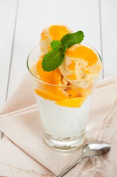 Mango ice cream with fresh mango and whipping cream in a glass