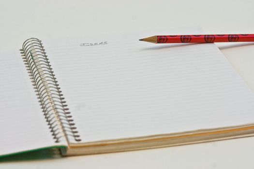 A wire bound notebook and pencil open with the word in english "ideas" on the top of the page.