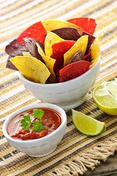 Bowl of salsa with colorful tortilla chips and lime